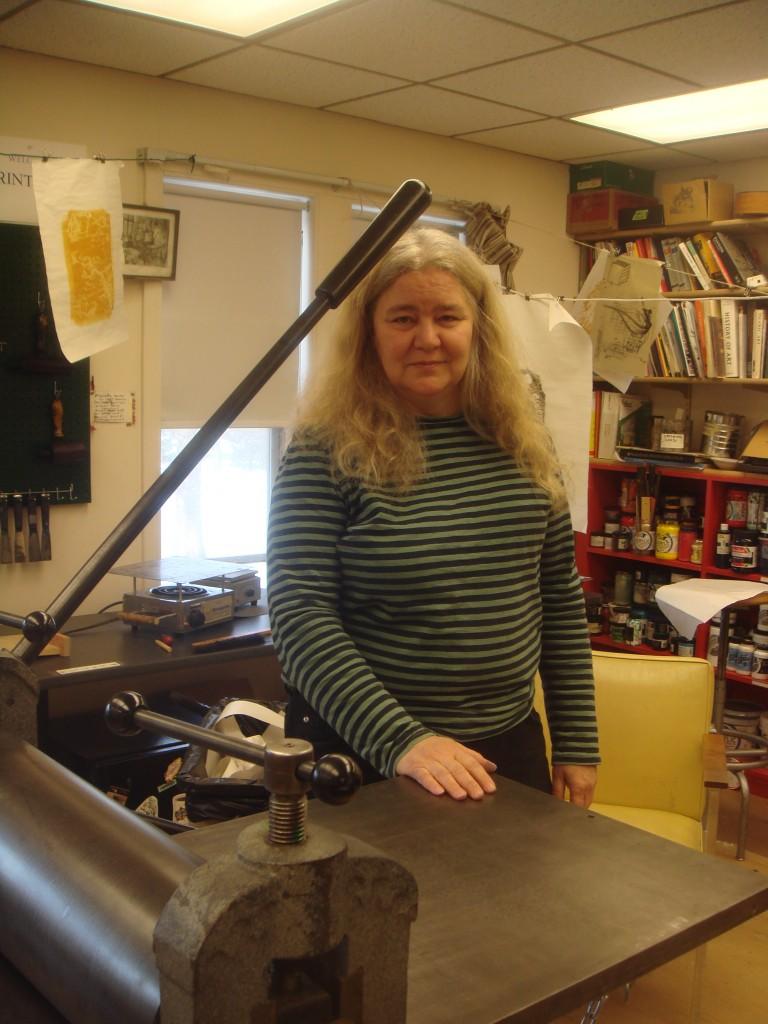 Professor Ruthann Godollei poses with the printing press in the Studio Art’s makeshift Printland, located on the third floor of the Lampert Building. (Photo by Amy Lebowitz.)