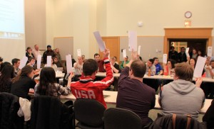 25 placards went into the air Tuesday night as MCSG unanimously passed a resolution calling on the school to commit to hiring more faculty members of color. Over 100 supporters packed the Weyerhaeuser Boardroom Tuesday night to express support for the bill. Photo courtesy of Emma Pulido ’16.