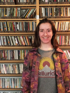 Franki Gillis ’20 poses next to WMCN’s immense CD collection. Photo by Lily Hannaher ’19.