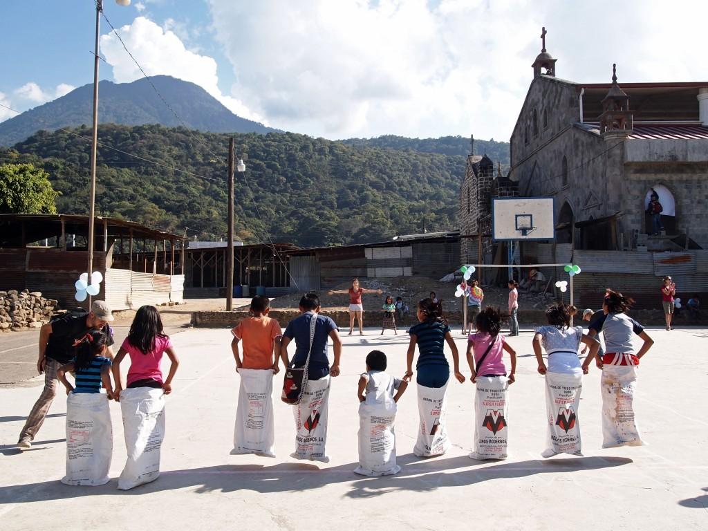 Guatemalan children compete in sack races during a carnival led by Rising Minds participants.