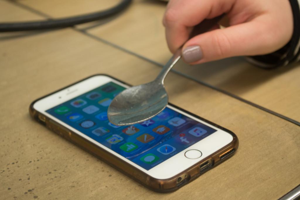 A student tests the response of a smartphone’s touchscreen with a metal spoon. *Photo by Josh Koh ’18.*