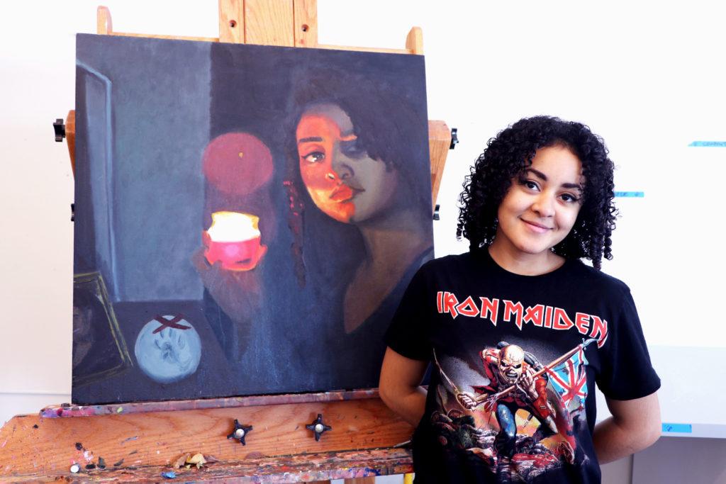 Aroura Bruins ’18 poses next to her canvas self-portrait, inspired by Caravaggio. Photo by Celia Heudebourg '18