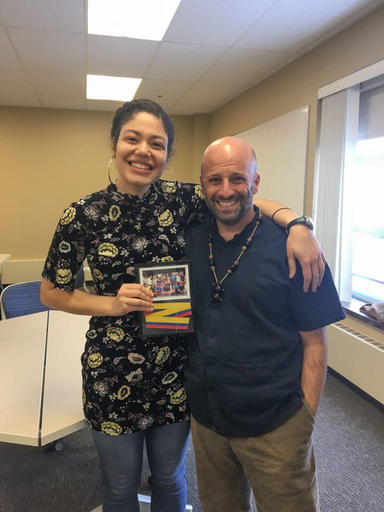 Giselle Lora ’18 with Rehearsing Change program director, Daniel Bryan, with an award made of a section of the ribbon from the opening ceremony of the new stage in La Mariscal, Ecuador, a project Lora proposed while studying away. 