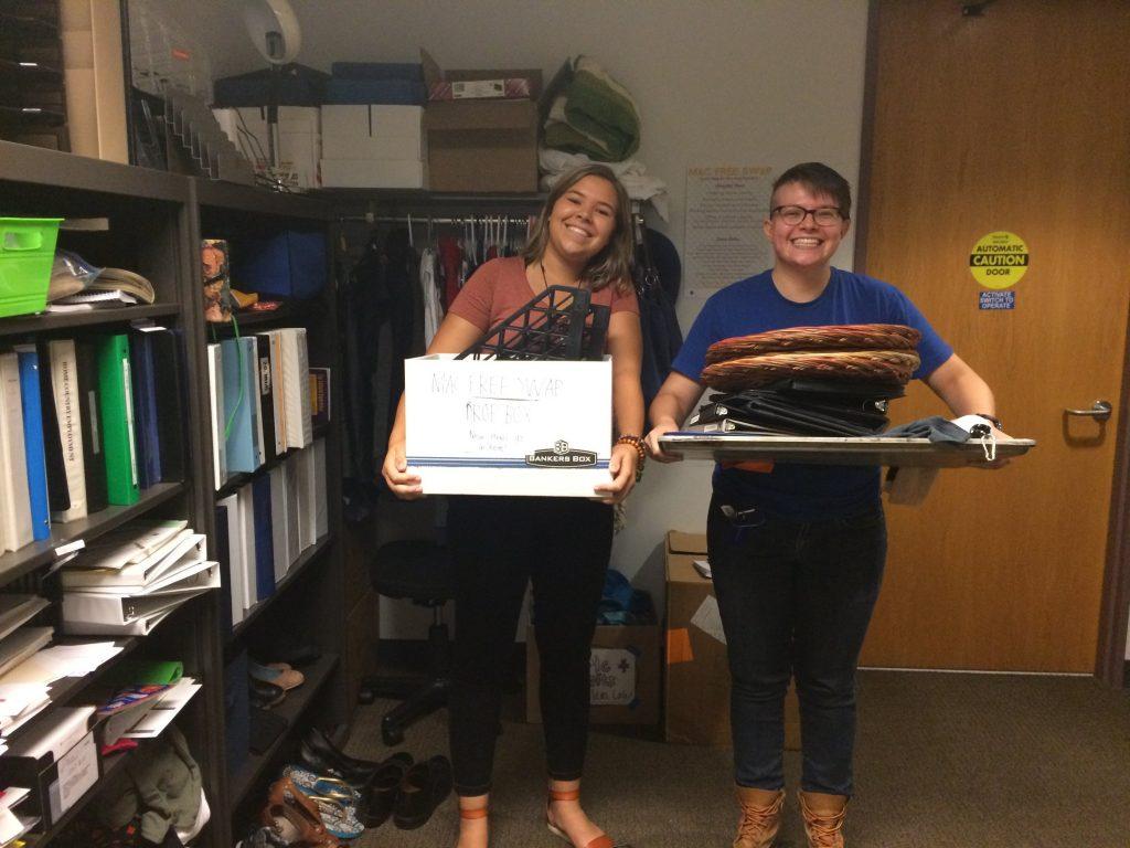 Aubrey Arnt ’21 and Izzy Ryde ’19 pose with new donations in theFreeSwap.  Photo courtesy of Macalester Sustainability Office.