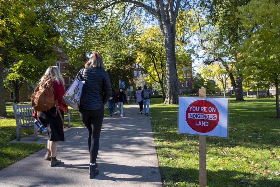 Students walk along Old Main lawn next to a sign from PIPE in honor of Indigenous Peoples Day. Photo by Kori Suzuki 21.