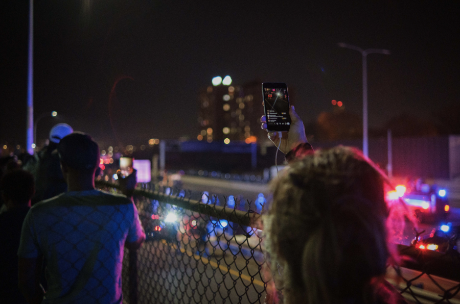 A bystander livestreams from the street overlooking I-94 as Minnesota State police surround and arrest more than 600 people calling for all votes to be counted in the presidential election on the highway below on November 4, 2020. Photo by Kori Suzuki 21.